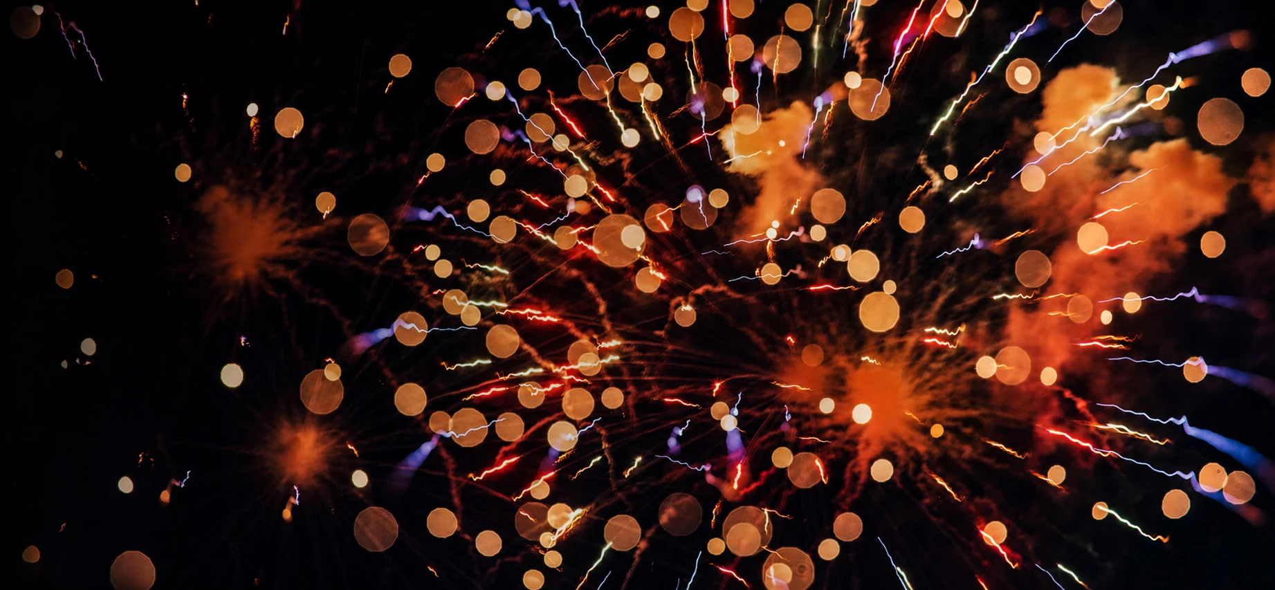 Abstract orange, gold, and blue fireworks against the night sky