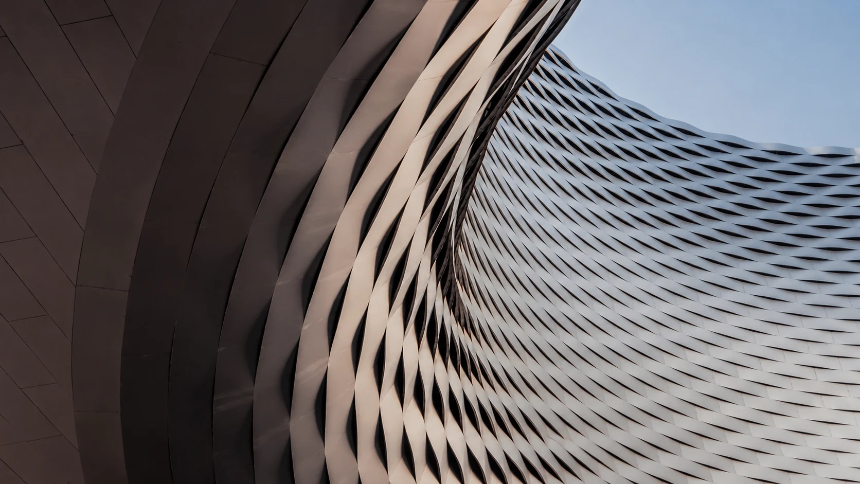 Curving metallic architectural facade with repeating sculptural fins